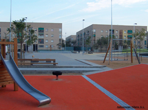 Zona de juego con pavimento de caucho rojo y un tobogán